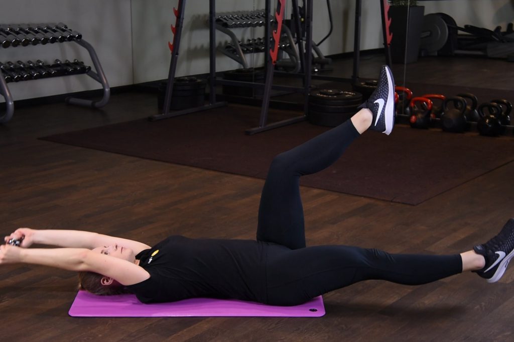 Opuszczanie nogi i rąk z hantlą w pozycji martwego robaka - dead bug