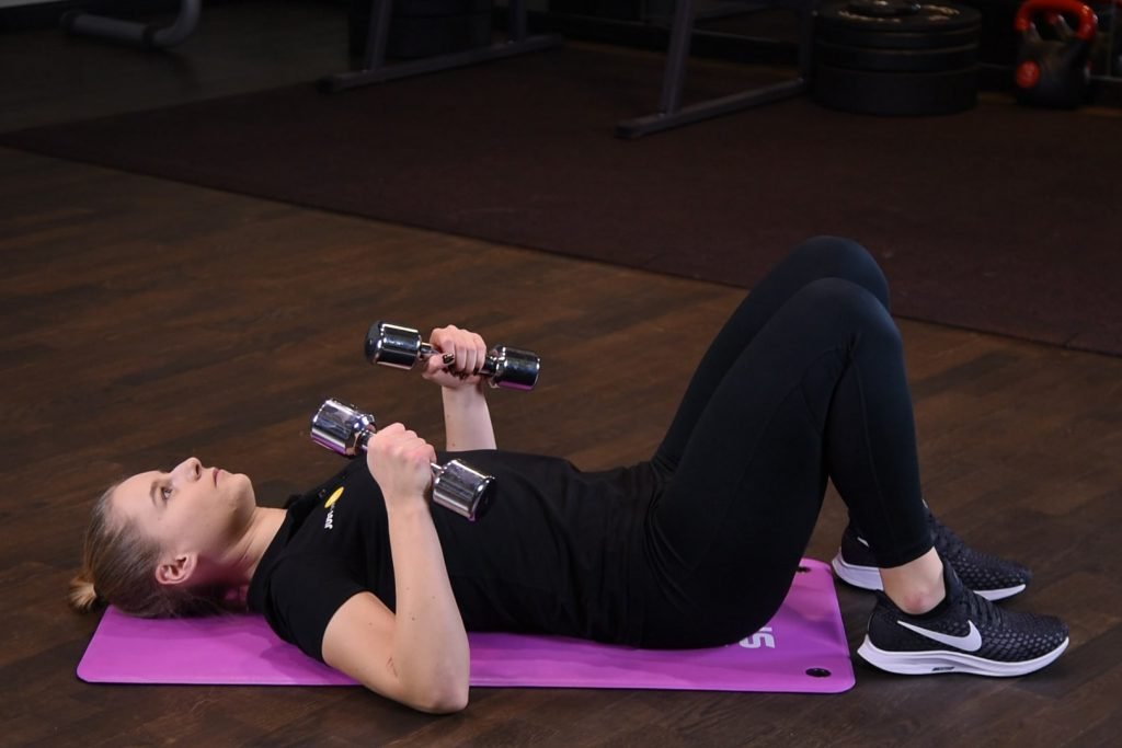 Wyciskanie hantli leżąc na ziemi