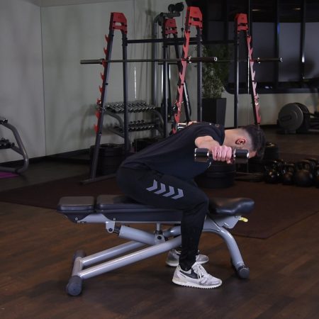 Unoszenie hantli na boki w opadzie tułowia siedząc z głową w kolanach Unoszenie hantli na boki w opadzie tułowia siedząc z głową w kolanach