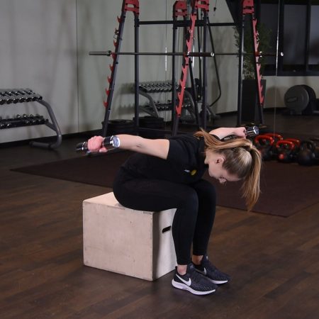 Unoszenie hantli na boki w opadzie tułowia siedząc z głową w kolanach Ćwiczenie unoszenie hantelek na boki w opadzie tułowia siedzac i pochylajac sie w kolana