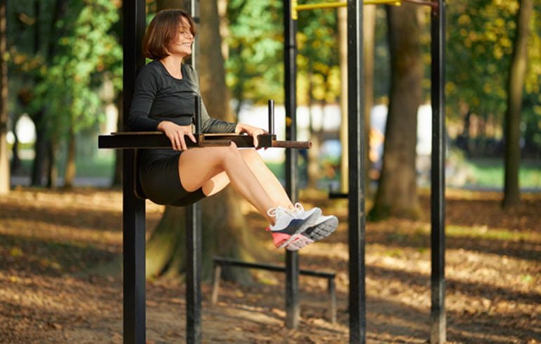 kobieta ćwicząca w parku na drążkach