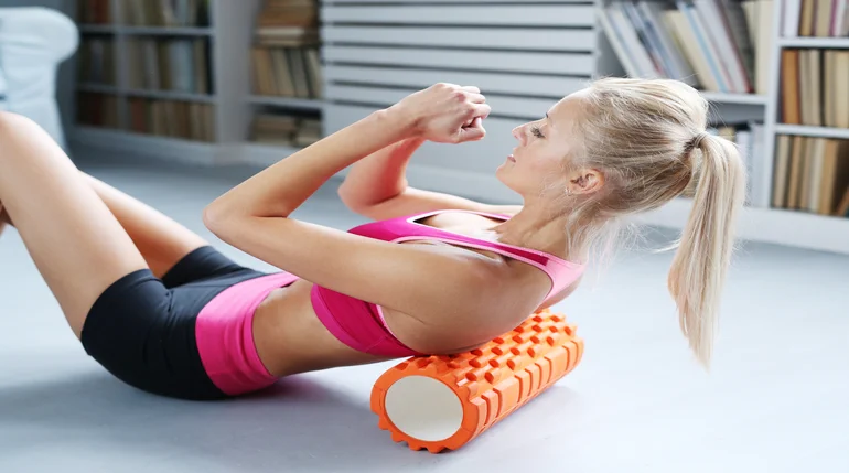 kobieta poprawiająca ukrwienie mięśni za pomocą rollera