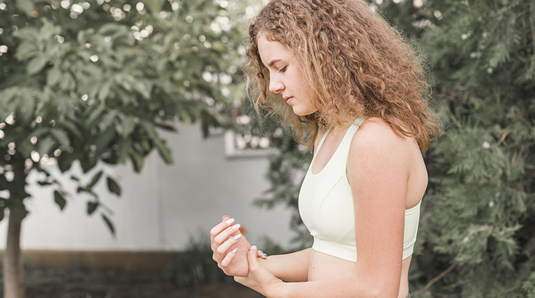 kobieta uciskająca bolące cieśni nadgarstka