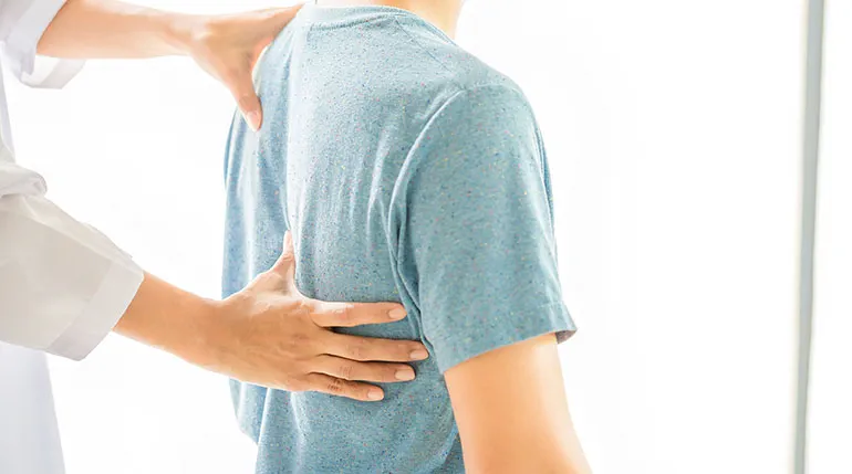 lekarz bada kręgosłup mężczyzny