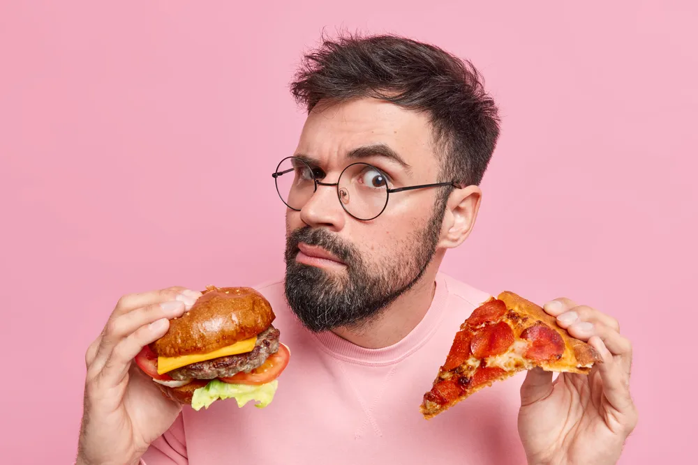 mężczyzna zastanawia się czy warto jeść fast foody