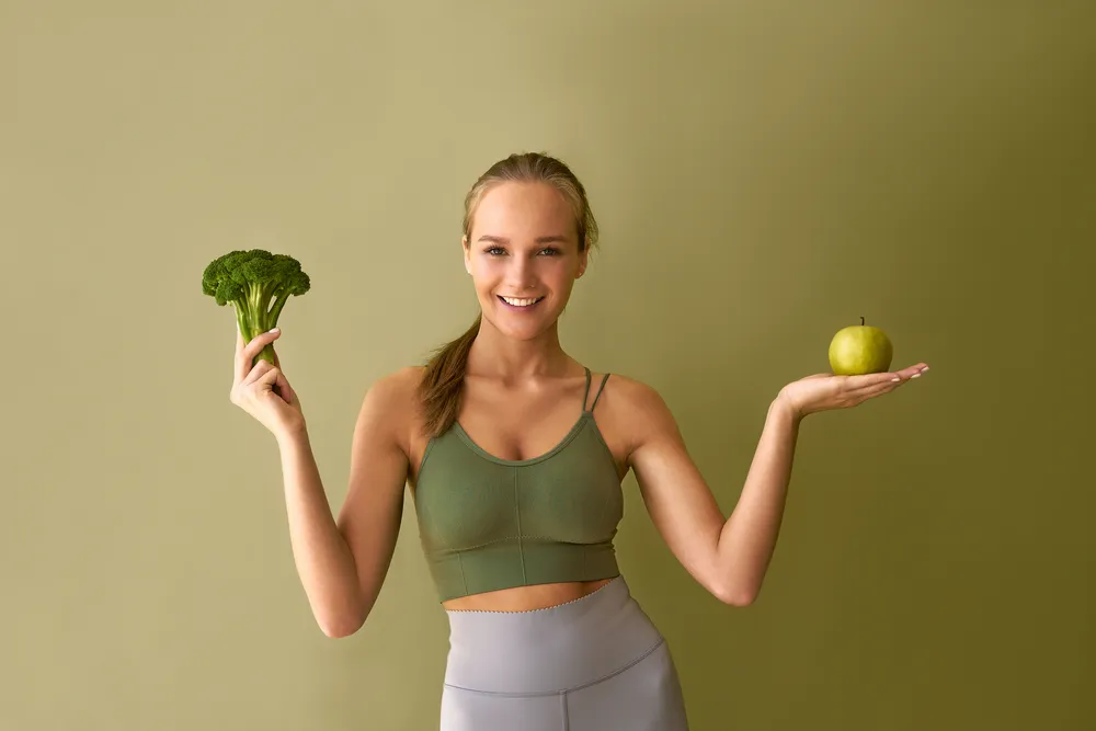 uśmiechnięta dziewczyna brokuł i jabłko na podwyższoną histaminę