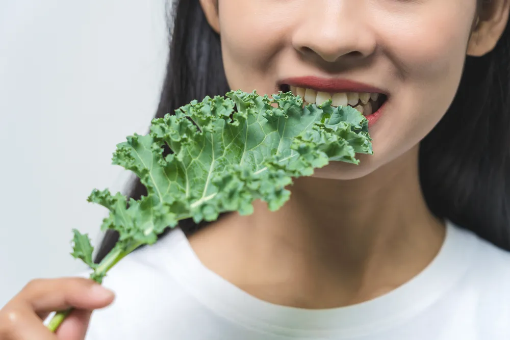 kobieta zjada świeży jarmuż