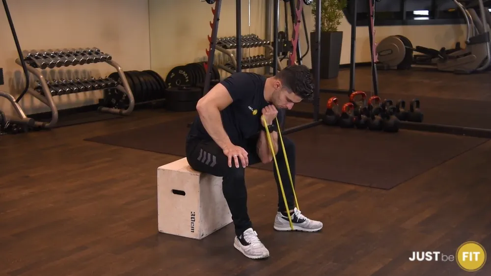 Uginanie ramienia z gumą mini band w oparciu o kolano ćwiczenia na biceps