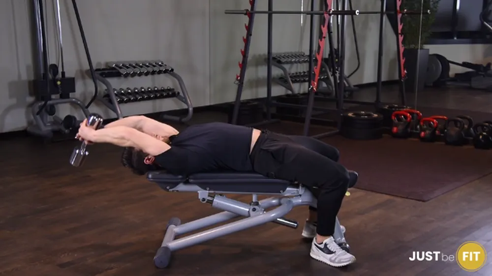 Przenoszenie hantla za głowę w leżeniu tyłem