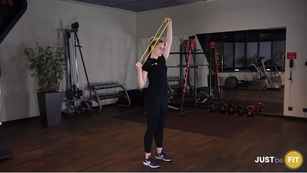 ćwiczenia na plecy ściąganie gumy mini band jednorącz za głowę