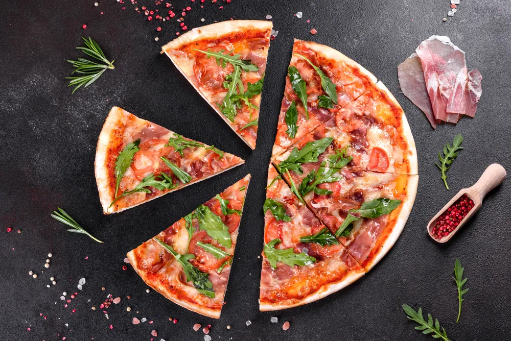 pizza z sosem pomidorowym rukolą i innymi dodatkami