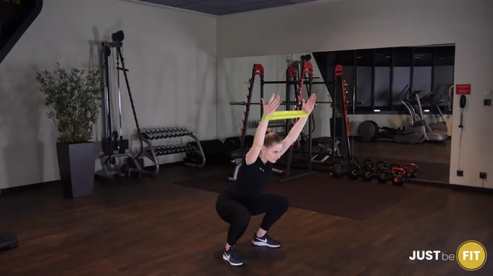 Przysiad z gumą mini band z rękami nad głowę OHS