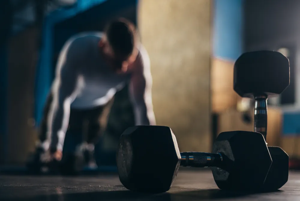mężczyzna i ciężary które należy odpowiednio dopasować do rodzaju treningu