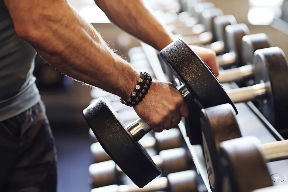 mężczyzna dobiera obciążenie do treningu